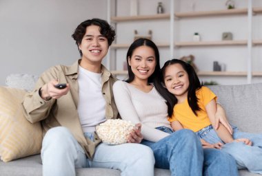 Üç aile ferdi, evde sıcak bir film gecesinin tadını çıkarıyor. En sevdikleri filmi rahat bir oturma odasında izlerken patlamış mısır ve gülümseme paylaşıyorlar..