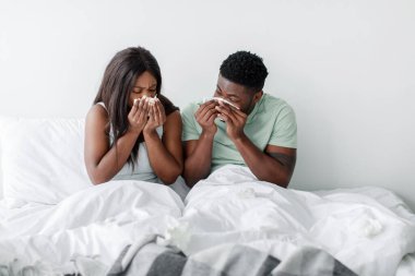 Yataklarında üzgün bir çift oturuyordu. Her ikisi de yüzlerine kağıt mendil tutarlar. Yumuşak ışıklı bir yatak odasında zor zamanlarında birbirlerine destek olurlar..