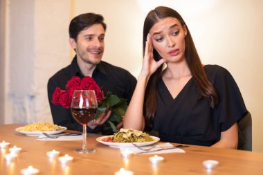 Bir adam samimi bir akşam yemeği sırasında bir kadına bir buket kırmızı gül sunar. Bir tabak makarna ve bir bardak şarapla eğlenirken kendinden emin görünmüyor. Yumuşak mum ışığı ortamı hazırlar..