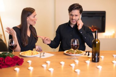 Bir çift evdeki samimi akşam yemeği sırasında hararetli bir tartışma yaşıyor. Kadın hayal kırıklığına uğramış gibi görünüyor. Adamın dikkati telefonda, mum ışığıyla çevrili..