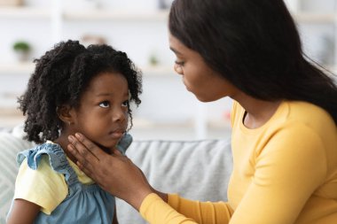 Bir anne sıcak ve davetkar bir oturma odasında kızıyla nazikçe konuşuyor. Yürekten bir anı paylaşıyorlar, öğleden sonra ışığında sevgi ve anlayış bağı gösteriyorlar..