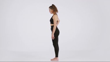 Bir kadın yoga seansına katılır, esneklik ve rahatlama teknikleri üzerinde çalışır. Zarafet ve farkındalığı somutlaştıran pürüzsüz bir yüzeyde kendine güvenle duruyor..