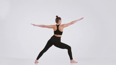 Bir kadın yoga pozu verir, güç ve esneklik gösterir. Aktivite için giyinmiş, sağlıklı bir yaşam tarzı ve refahı temsil ediyor..