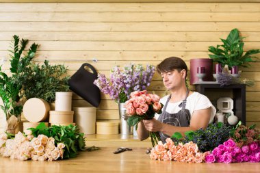 Küçük işletme. Erkek çiçekçi gül buketi çiçekçi dükkanı sayaç masasında yapma. Adam asistan veya çiçek tasarım Studio, dekorasyon ve düzenlemeler yapma sahibi. Çiçek teslimat, siparişi oluşturma