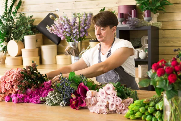 Küçük işletme. Erkek çiçekçi gül buket çiçek dükkanında yapma. Adam asistan veya çiçek tasarım Studio, dekorasyon ve düzenlemeler yapma sahibi. Çiçek teslimat, siparişi oluşturma