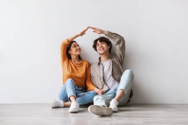 Yeni boş bir dairede, mutlu bir Asyalı çift yerde oturuyor. Elleriyle bir çatı yapıyorlar ve birbirlerine gülümsüyorlar, birlikte hareket günlerinin tadını çıkarıyorlar..