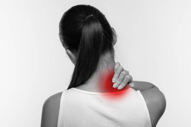 Tanınmayan bir kadın kas stresinden dolayı oluşan ağrıyı hafifletmek için boynuna masaj yapıyor. Ağrıyan bölgesindeki kırmızı bir belirti ile basit bir beyaz arka plana karşı rahatsızlık gösteriyor..