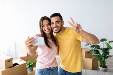 Birkaç gülümseme ve yeni evlerinde taşınan kutularla dolu bir selfie için poz vermek. Yeni başlangıçları için mutlu ve heyecanlılar..