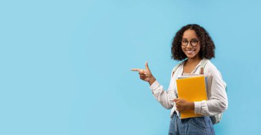 Güzel siyah bir kız öğrenci elinde defterler ve bir sırt çantası tutarken kameraya gülümsüyor. Bölgeyi parlak mavi bir arka planda doldurmak için eğitici ilanlar veren boş bir alanı işaret ediyor..