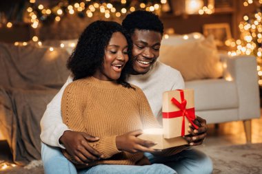 Heyecanlı genç siyah çift birlikte bir Noel hediyesi kutusu açıyor..