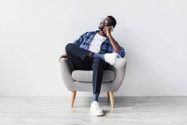 Neşeli genç siyah bir adam koltukta rahat bir şekilde oturur ve bir arkadaşıyla canlı bir telefon görüşmesi yapar. Sahne düz beyaz bir stüdyo duvarına dayanıyor, rahat bir atmosfer yaratıyor..