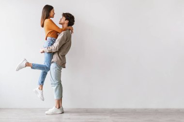 Genç Asyalı çift, parlak bir stüdyoda sevgilisini kollarında tutan adamla dikiliyor. Şefkatli bir anı paylaşıyorlar, beyaz bir duvara karşı sevgi ve şefkat gösteriyorlar..