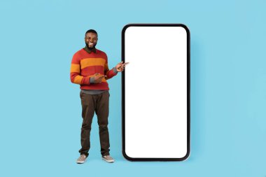 Şuna bak. Beyaz Ekranlı Büyük Boş Akıllı Telefonu Gösteren Siyah Adam Mobil Uygulama Tasarımı, Mavi Arkaplan, Mobil Fotokopi için Bedava Kopya Alanı Gösteren Gülümseyen Afrikalı Amerikalı Adam