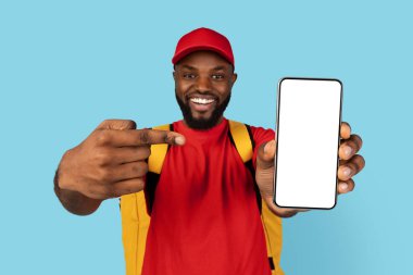 Uygulamada Düzen. Beyaz Ekran ile Boş Akıllı Telefon 'u işaret eden neşeli siyah teslimatçı, termal sırt çantası giyen Afrikalı Amerikan kurye yiyecek teslimatı için mobil uygulama öneren,