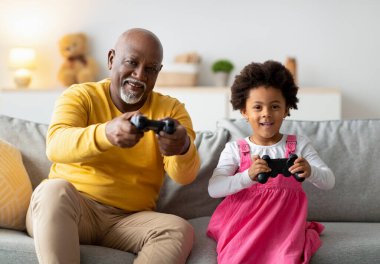 Küçük bir kız ve büyükbabası rahat bir oturma odasında video oyunu oynamaktan zevk alıyorlar. Kahkaha ve heyecanı ellerinde joysticklerle paylaşıyorlar, kalıcı anılar yaratıyorlar..