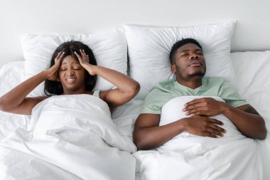 Bir erkek, yatakta başı dertteyken huzur içinde uyuyakalır. Çarşafları bembeyaz ve oda yumuşak bir şekilde aydınlatılmış. Bu da sabahın erken saatleri olduğunu gösteriyor..