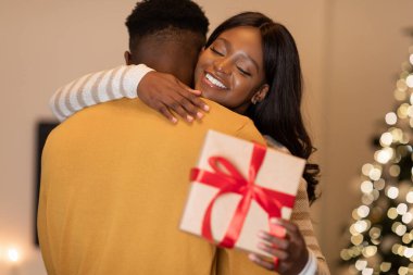 Bir çift, kış tatilini kutlarken içeride birbirlerini kucaklıyor. Karınız güzel bir hediyeyle sarılır ve birlikte güzel bir anı paylaşırlar..