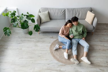 Mutlu bir çift hafta sonunu evde birlikte geçirir. Kanepenin yanında otururlar, akıllı telefon kullanarak uygulamaları keşfederler ve birbirlerine eşlik ederler..