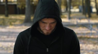 Siyah kapüşonlu genç bir adam sonbahar yeşillikleriyle çevrili bir parkta koşuyor. Koşarken sağlıklı bir yaşam tarzını benimserken dikkatle antrenmanına odaklanıyor..