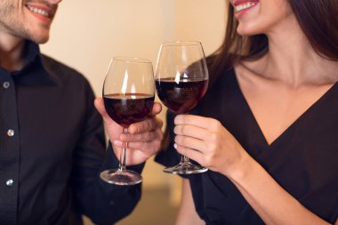 Bir çift kırmızı şarap kadehlerini kaldırır, keyifli bir kadeh kaldırır. Zarif giyinmişler, romantik bir olayı kutluyorlar. Atmosfer sıcak ve samimi, bağlantılarını güçlendiriyor..