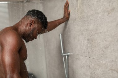 Genç siyah bir adam sıcak bir duş alıyor, düşen suyun altında dinleniyor. Gözleri kapalı duruyor, kapalı bir banyoda yalnızlığın tadını çıkarıyor, vücut bakımına odaklanıyor..