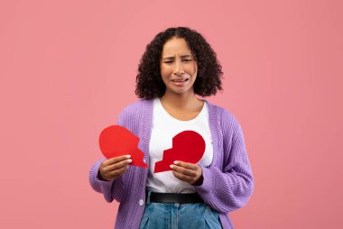 Genç siyah bir kadın pembe bir arka plana karşı duruyor, elinde kağıt bir kalbin iki yarısı var. Görünürde üzgün ve ağlıyor. Romantik bir ilişkinin sonundaki duyguları yansıtıyor..