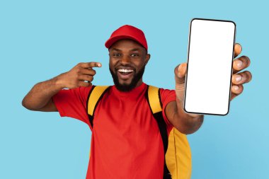 Yemek Teslimatı Uygulaması. Beyaz ekranlı boş akıllı telefonu işaret eden termal çantalı siyah kurye adam, Üniformalı Afrikalı teslimatçı Çevrimiçi Sipariş İçin Mobil Uygulama, Mobil Mobil Mobil Uygulama,