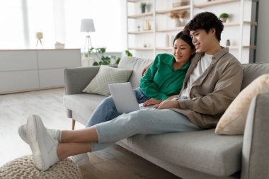 Çift rahat bir kanepede birlikte oturur, bir dizüstü bilgisayarla online toplantı yapar ve film izlerler. Işıkla dolu parlak bir salonda gülümsemeleri ve samimi anları paylaşıyorlar..