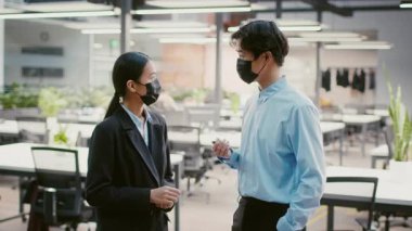 İki genç Asyalı profesyonel yeşillik ve parlak ışıkla dolu çağdaş bir ofiste sohbet ediyorlar. İkisi de maske takıyor ve nişanlı ve dost canlısı görünüyorlar..