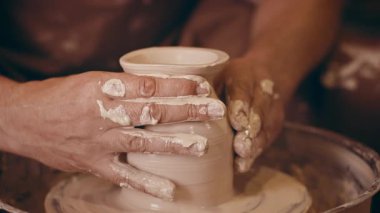 Orta yaşlı bir adam çömlek atölyesinde elleri ile kilden bir vazoyu şekillendirmeye odaklanır. Titiz hareketleri el yapımı sanat ve dekorasyon tutkusunu gözler önüne seriyor..