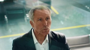 Takım elbiseli yaşlı bir adam çağdaş bir ofiste otururken derin düşüncelere dalıyor. Ambiyans, kıdemli bir iş adamı olarak statüsünü vurgulayan bir şirket yaşam tarzına işaret ediyor..