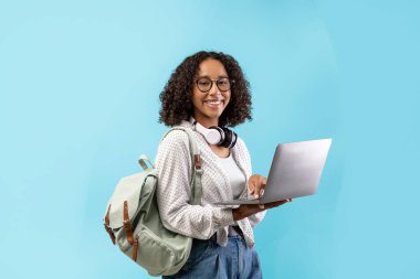 Kıvırcık saçlı, gözlüklü, dizüstü bilgisayarlı, kulaklık takan ve sırt çantası olan neşeli siyah bir kadın. Tecrit süresince uzaktan öğrenmeyi temsil ediyor..