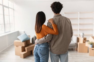 Genç bir çift yeni oturma odalarında birlikte hareket etmekten zevk alırken birbirlerine sarılıyorlar. Karton kutular etrafa saçılmış, yeni hayatlarının başlangıcını simgeliyor..