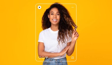 Kıvırcık saçlı bir kadın saçının bir telini tutarken parlak bir şekilde gülümsüyor. Parlak sarı bir arka planın önünde duruyor, neşeli tarafını ve günlük tarzını sergiliyor..