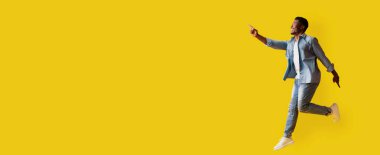 Açık mavi takım elbiseli ve kot pantolonlu bir adam sevinçle yukarı bakıyor. Harekete geçti, enerji ve pozitiflik yayıyor, canlı atmosferi arttıran canlı sarı bir zemin üzerine kurulmuş..