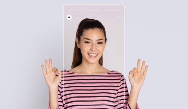 Bir kadın hafif bir arka planda duruyor, el hareketi yaparken gülümsüyor. Kendinden emin ve dijital bir arayüzle meşgul görünüyor. Teknoloji ve pozitifliğin bir karışımını gösteriyor..