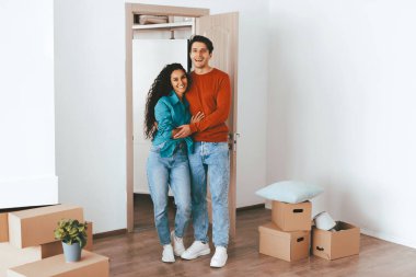 Genç bir çift yeni dairelerinde kutuları taşırken gülümsüyor. Birlikte yeni maceralarına başlarken birbirlerini kucaklayarak heyecan gösteriyorlar..