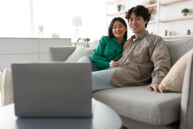 Sevgi dolu iki eş kanepede oturup dizüstü bilgisayarda film izlerler. Hafta sonu boyunca sıcak ve mutlu bir atmosfer yaratarak evde vakit geçirmeyi seviyorlar..