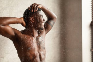 Afrikalı genç adam şık bir banyoda duşun altında saçını yıkıyor. Gözlerini rahatlıkla kapatıyor. Su, kaslı vücudunun üzerine çağlayarak ferahlatıcı bir an yaratıyor..