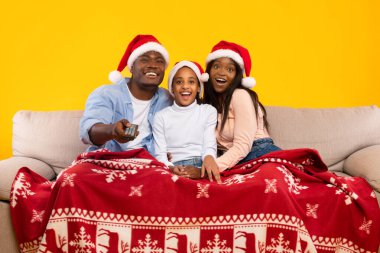 Mutlu bir siyah aile, Noel filmlerini izlerken, kırmızı Noel Baba şapkaları takan bir kanepede sarılır. Sıcak bir battaniyeye sarılıp, bayram boyunca birlikte eğleniyorlar..