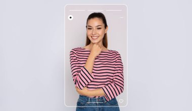 Genç bir kadın pembe ve siyah çizgili bir gömlek giyerken neşeli bir gülümsemeyle poz veriyor. Tarzı, basit bir arka plandaki kendine güvenen duruşu tarafından vurgulanıyor..