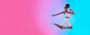 Enerjik bir atlet, etkileyici bir fiziksel yetenek sergileyerek havada sıçrıyor. Arkaplanda canlı pembe ve mavi gölgeler var. Anın yoğunluğunu vurguluyorlar..