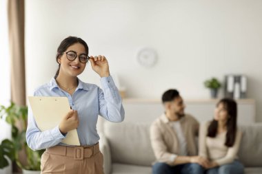 Genç evli bir çiftle verimli bir seanstan sonra mutlu bir Arap kadın evlilik danışmanının portresi. Danışman, müşterilerinin ilişki sorunlarını çözmelerine yardım ederken kendinden emin bir şekilde gülümsüyor..