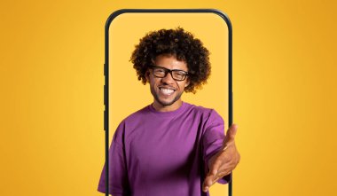 Kıvırcık saçlı ve gözlüklü neşeli bir adam sanki birine hoş geldin der gibi elini uzatıyor. Parlak sarı bir arka plana karşı duruyor, pozitif ve sıcak bir hava yayıyor..