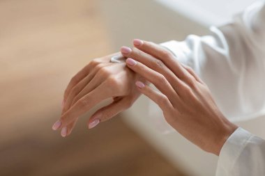 Tanınmayan genç bir kadın banyodan sonra kollarına el kremi sürüyor. Parlak, rahat bir odada cilt bakımına odaklanıyor. Kuru cilt için hidrasyon sağlıyor..