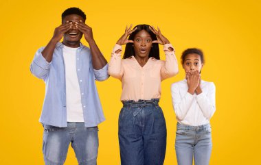 Üç aile ferdi, canlı sarı bir zemin karşısında yan yana dururlar..