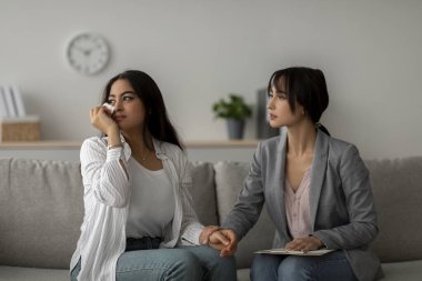 Genç bir psikolog, psikoterapi seansı sırasında ağlayan Orta Doğulu bir kadına destek oluyor. Terapist, duygular ve düşünceler hakkında konuşurken hastaların elini tutar..