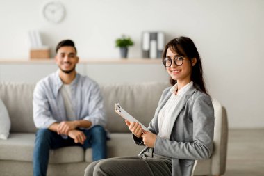 Mutlu bir kadın psikolog ve genç bir Arap adam verimli bir terapi seansından sonra parlak bir ofiste birlikte gülümsüyorlar..