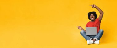 Neşeli genç bir adam önünde dizüstü bilgisayarla yerde bağdaş kurarak oturuyor. Gülümser ve coşkuyla işaret eder. Sahneye enerji katan parlak sarı bir zemin gösterir..