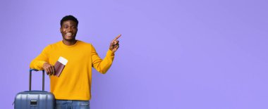 Parlak sarı bir kazak giyen bir adam bir bavulun yanında duruyor. Geniş bir şekilde gülümsüyor ve bir elinde pasaport tutarak coşkuyla işaret ediyor. Arka plan canlı bir mor..